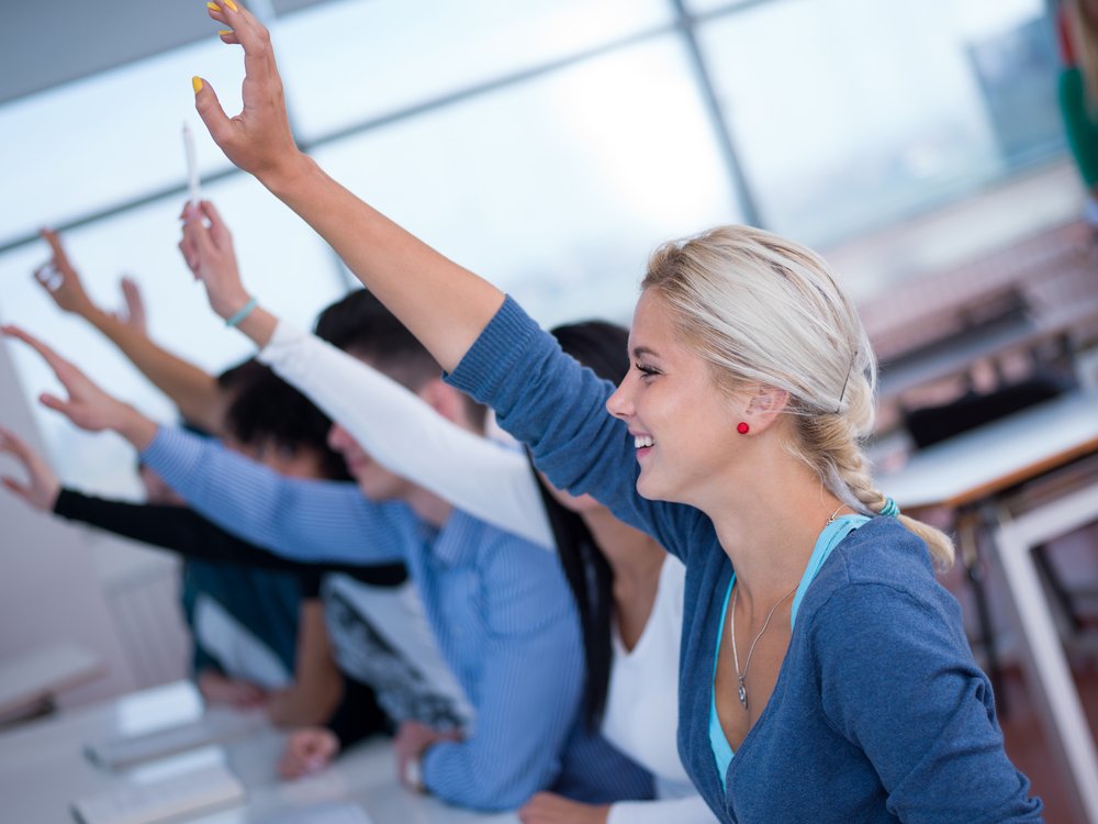 students group raise hands up in classroom