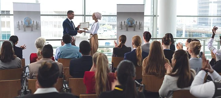 A person awarding a certificate to someone in front of an audience