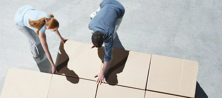 Two people putting together a large puzzle or floor tiles together